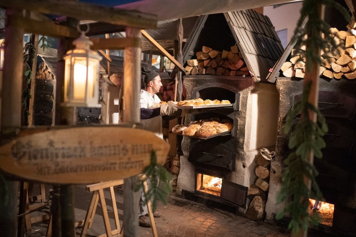 Bäcker auf dem Mittelaltermarkt befüllt den Ofen mit Brot