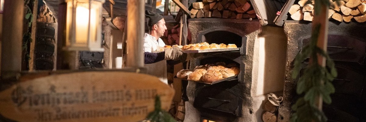 Bäcker auf dem Mittelaltermarkt befüllt den Ofen mit Brot